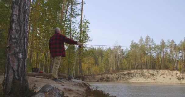 Pêche à la ligne dans un lieu écologique, l'homme est debout sur la rive du lac forestier seul et la tige de moulage dans l'eau, passe-temps et temps de détente — Video