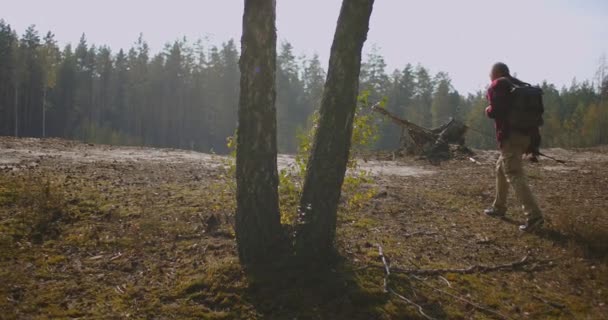 Hombre de mediana edad con varilla en la mano está caminando a la orilla alta del río y ver la superficie del agua desde la parte superior — Vídeo de stock