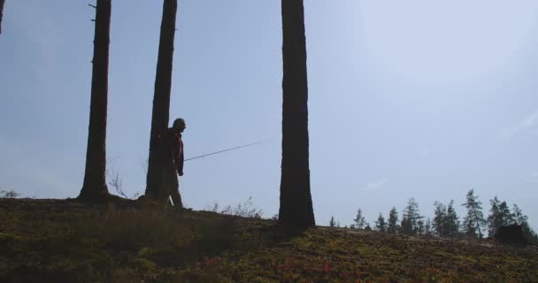Ensam fiskare med spö i handen går på naturen, siluett utsikt mot blå himmel, slow motion skott — Stockvideo