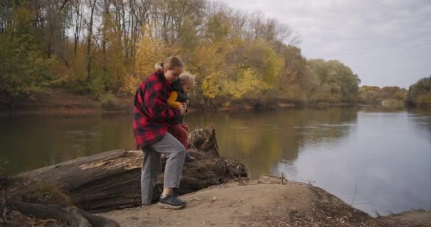 Gelukkig moeder en haar kleine kind lopen samen in de herfst park met de rivier, ademen frisse herfstlucht — Stockvideo