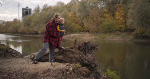 Loving mother is speaking to his little son about nature during walk at autumn forest, spending time together — Stock Video