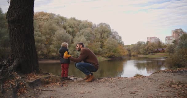 Familjen vila i höstskogen, far talar till barn son och visar pittoreska sjö i skogen, vandring — Stockvideo