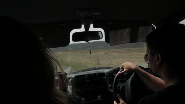 Pár jízda v autě přes pole, výhled z uvnitř auto. pravého kola — Stock video