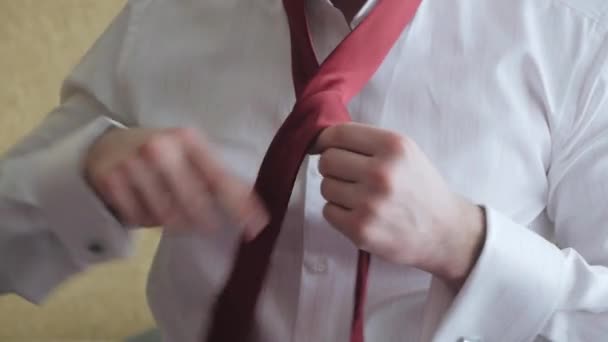 Мужчина в белой рубашке завязывает красный галстук на шее. Обучение вязанию галстука — стоковое видео