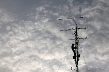 İşçiler telekomünikasyon kule ya da Polonyalılar, akşam, kırmızı gökyüzü günbatımı arka planda onarmak için tırmanma vardır
