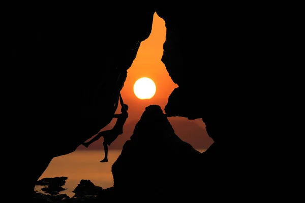 Rock climbing,Silhouette man between rocks with red sky sunset background