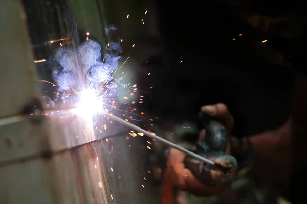 The reaction of welding wire and metal with smoke fire and sparkle light, The hands of the workers are welding.