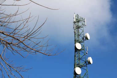 İletişim yapı kule mavi gökyüzü ve yapraksız ağaçları ile anten.