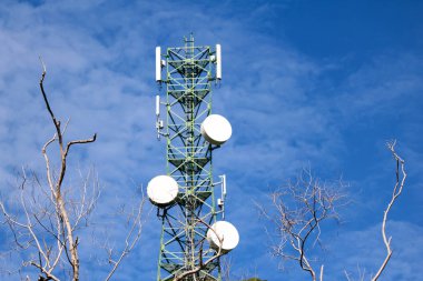 İletişim yapı kule mavi gökyüzü ve yapraksız ağaçları ile anten.