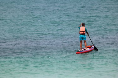 Raket pano veya Tayland tropik sahilde sörf tahtası ayağa zevk turist adam.