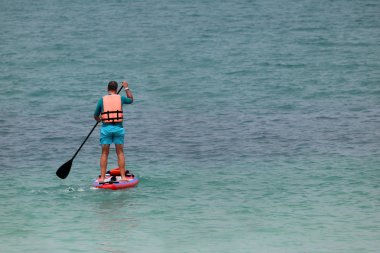 Raket pano veya Tayland tropik sahilde sörf tahtası ayağa zevk turist adam.