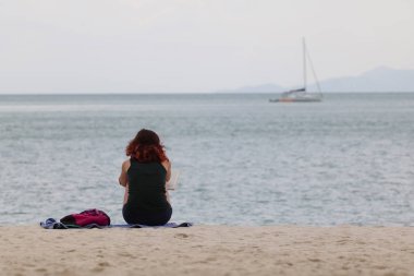 Turist kız akşam bir tropikal plaj rahatlatıcı bir kitap okuma. Tayland