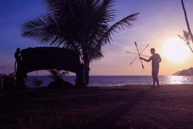 Adam iplik iletişim personeli veya sopa ile gündoğumu arka planda sabah sahilde.