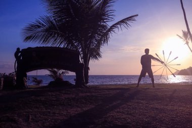 Adam iplik iletişim personeli veya sopa ile gündoğumu arka planda sabah sahilde.