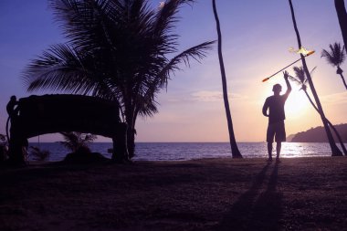 Adam iplik iletişim personeli veya sopa ile gündoğumu arka planda sabah sahilde.
