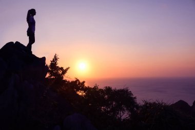 Mutlu kadın dağın günbatımında zevk. Siluet gökyüzü arka plan.