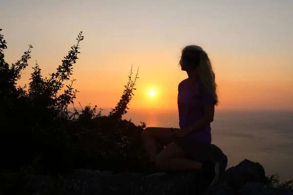 Happy woman enjoying on the top of the mountain at sunset. Silhouette sky background.