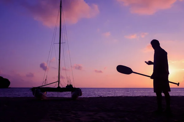 Hobie cat or catamaran on the beach at beautiful sunrise early morning, Silhouette asian man with paddle and sailing catamaran on the beach