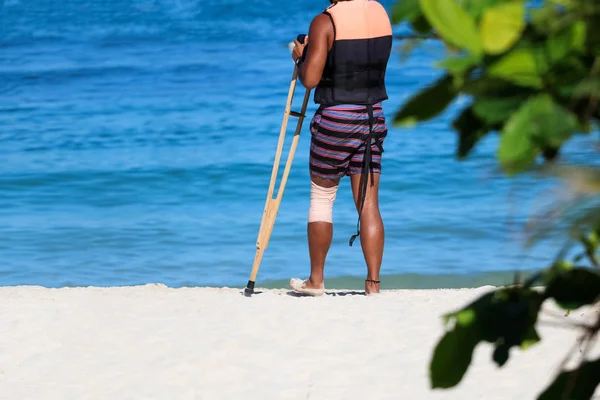 Accident tourist man are walking by crutches on the beach while travel , summer in Thailand.