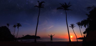 Bir milyon yıldız ve gündoğumu erken sabah Hindistan cevizi sahilde duran adamın panoramik manzara.