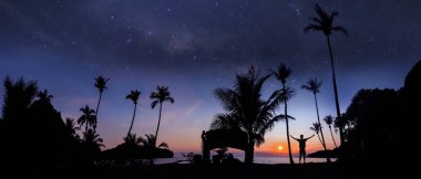 Bir milyon yıldız ve gündoğumu erken sabah Hindistan cevizi sahilde duran adamın panoramik manzara.