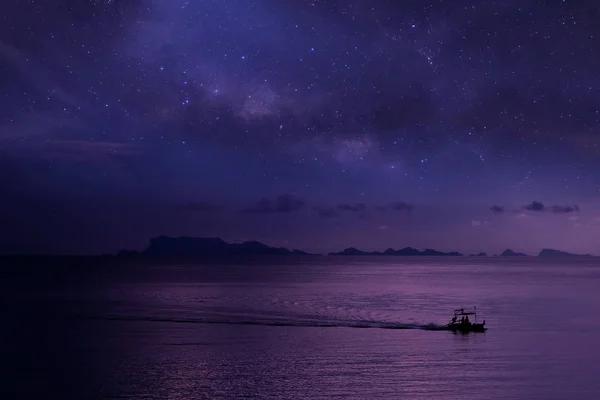 Yerel Balıkçılar denizde milyon yıldız gökada gökyüzü arka plan ile bir uzun kuyruk tekne.