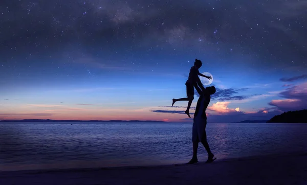 剪影父亲和女儿在海滩上与百万星星系 月亮和蓝天清晨 — 图库照片