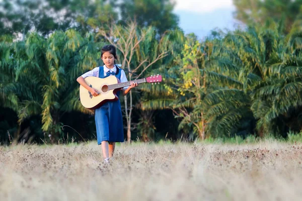 亚洲女学生在草坪上弹吉他 — 图库照片