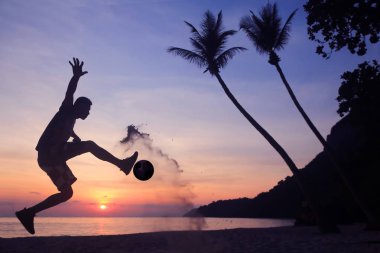 Asya adam sabah güneş doğarken kumsalda futbol oynamak.