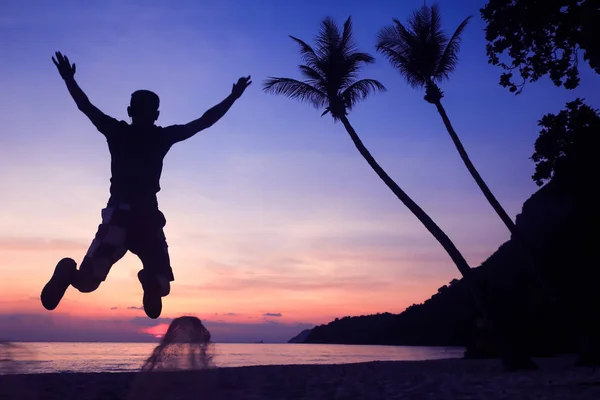 Aziatische man springen plezier op het strand bij zonsopgang — Stockfoto