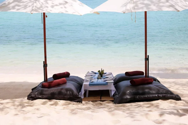 Bean bags with the white umbrella on the beach, set up for lunch — Stock Photo, Image
