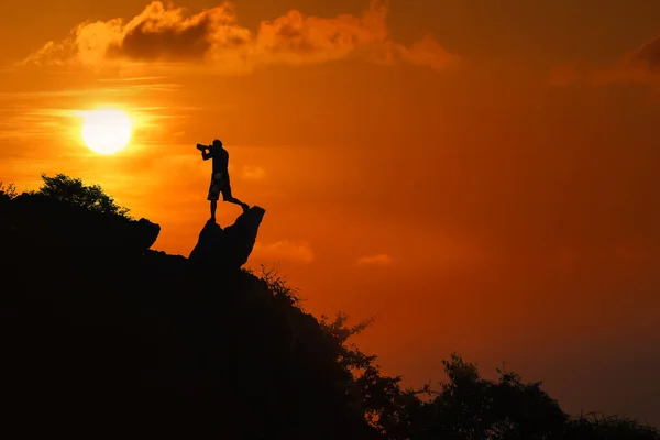 Silueta del fotógrafo en la cima de la montaña al atardecer cielo rojo —  Fotos de Stock