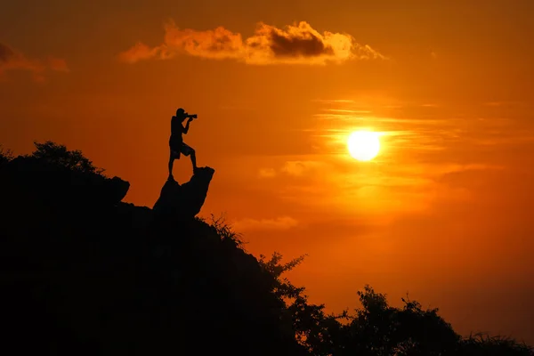 Silueta del fotógrafo en la cima de la montaña al atardecer cielo rojo —  Fotos de Stock