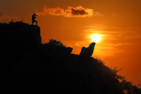 Silueta del fotógrafo en la cima de la montaña al atardecer cielo rojo —  Fotos de Stock