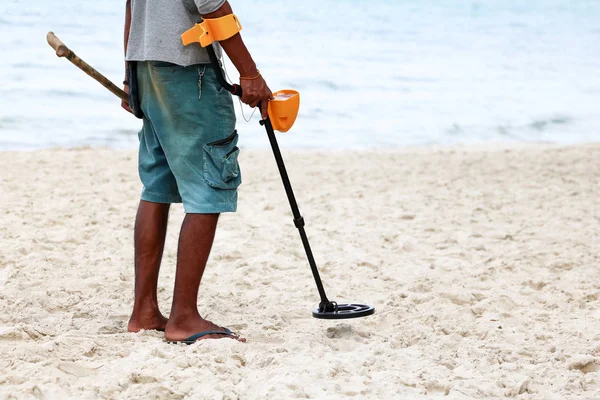 Aziatisch mannetje gebruikt metaaldetector om objecten op een strand te vinden — Stockfoto