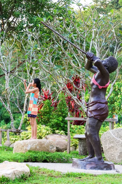 Азиатская девушка наслаждается с варварской статуей в общественном парке — стоковое фото