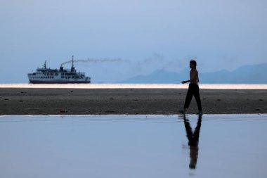 Asyalı kız sahilde gün batımı sırasında kendini zevk