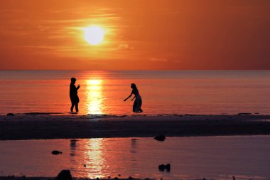 Asyalı çiftlerin siluet b gün batımı sırasında tadını çıkarıyor