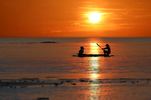 Silueta de pescadores locales remando pequeños botes a lo largo de la costa — Foto de Stock