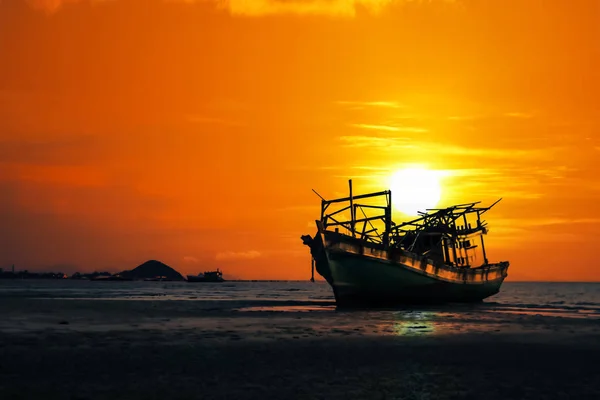 Старая разбитая лодка, брошенная на пляже на закате, Красное небо — стоковое фото