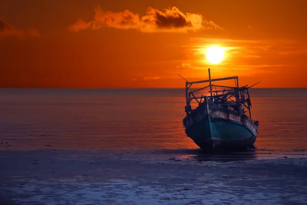 Barco viejo roto abandonado en la playa al atardecer, cielo rojo — Foto de Stock