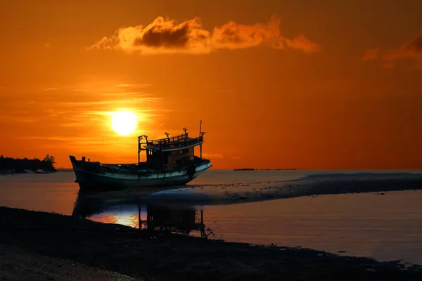 Vieux bateau cassé abandonné sur la plage au coucher du soleil, ciel rouge — Photo
