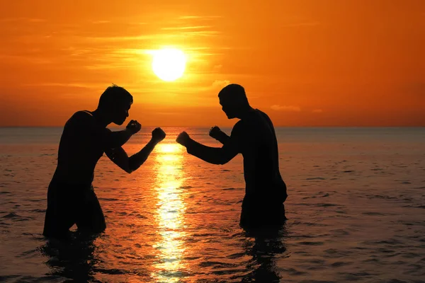 Aziatische man beoefenen van Thais Boksen op het strand van de zee bij zonsondergang — Stockfoto