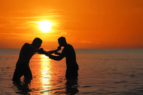 Aziatische man beoefenen van Thais Boksen op het strand van de zee bij zonsondergang — Stockfoto