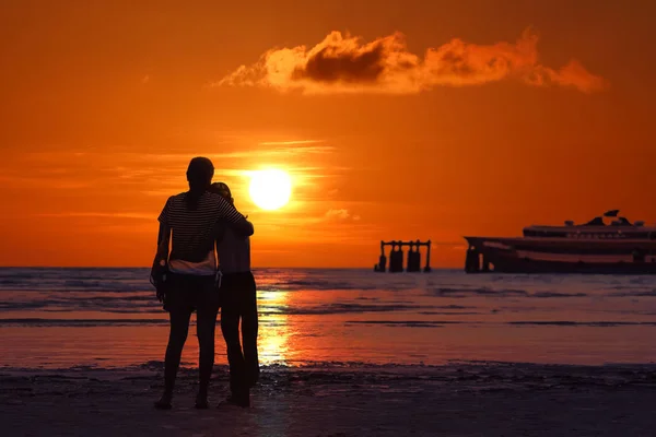 Moeder en dochter kijken naar zonsondergang op het strand. — Stockfoto