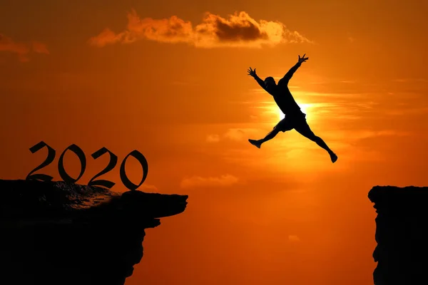 Das Silhouettenkonzept des neuen Jahres 2020, der Mensch springt und klettert — Stockfoto