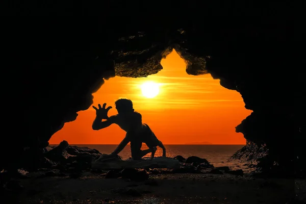 Caveman posture or action in the cave at sunset