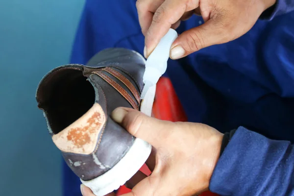 As mãos usam cola quente para reparar sapatos . — Fotografia de Stock