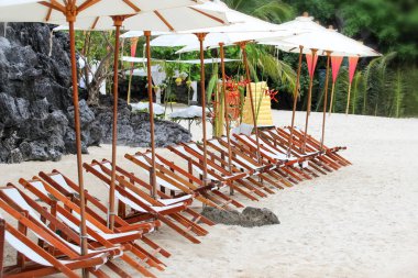 Tropik adada sahilde beyaz şemsiyeli sandalyeler