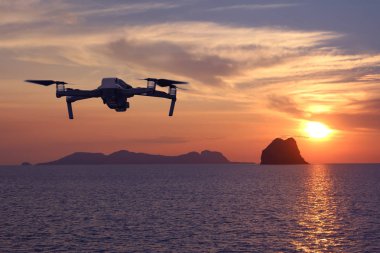 Gün batımında gökyüzünde uçarken drone'lar, Okyanus ve ada arka